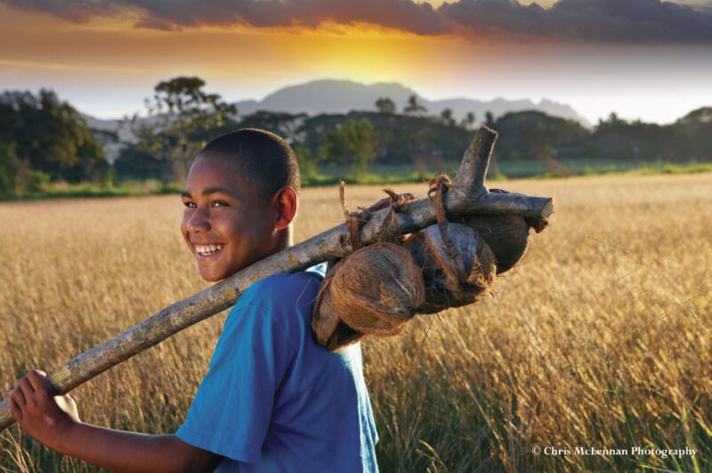 young boy with coconuts, early morning,  in front of "sleeping giant" mountains. Namaka. Fiji.model release 717