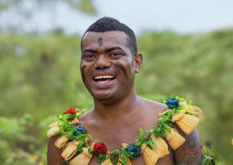Fijian man smiling in cultural clothing.